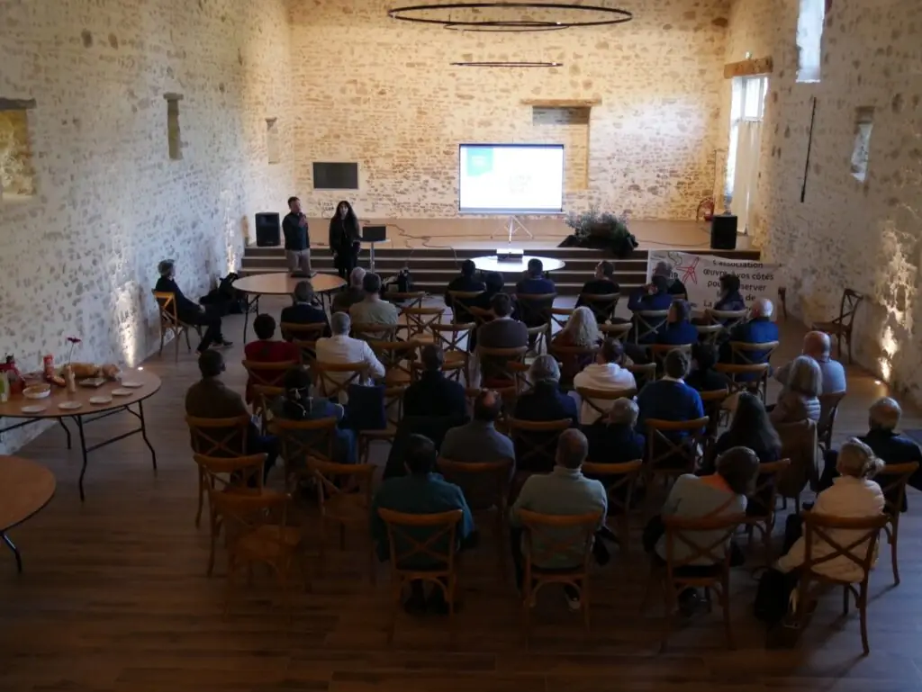 Assemblée générale d'association réunissant une centaine de participants dans la salle du château