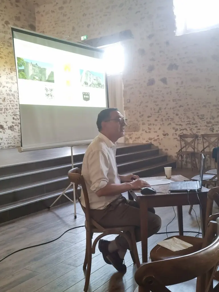 Intervenant animant une conférence depuis la scène surélevée de la salle de l'écurie